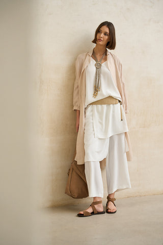 look elegante mujer en capas con vestido blanco fluido y chaqueta beige